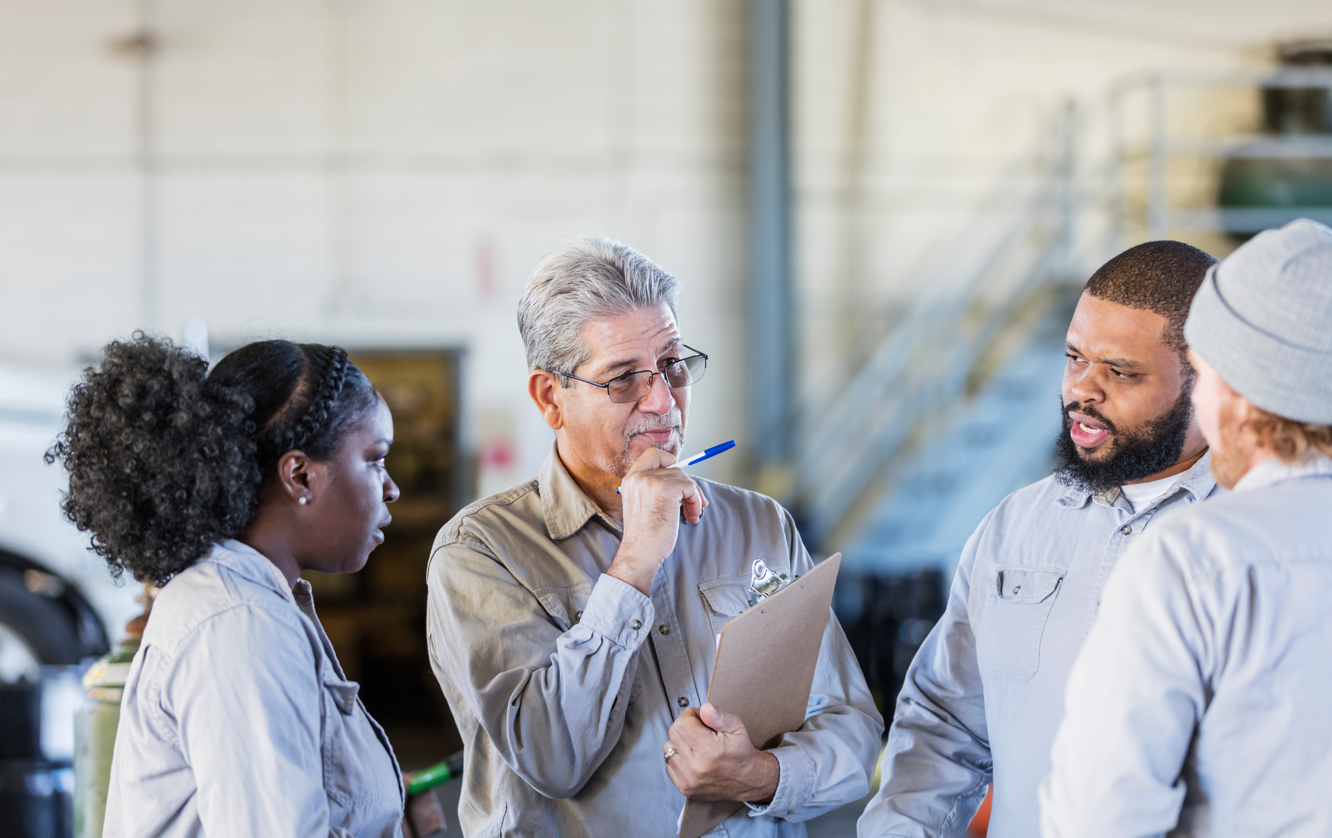 An auto repair shop owner meets with his team for a morning huddle.
