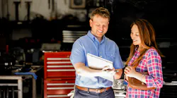 An auto technician reviews a warranty with a customer.