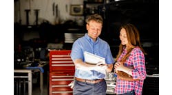 An auto technician reviews a warranty with a customer.