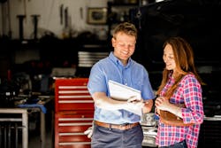 An auto technician reviews a warranty with a customer. An auto technician reviews a warranty with a customer.