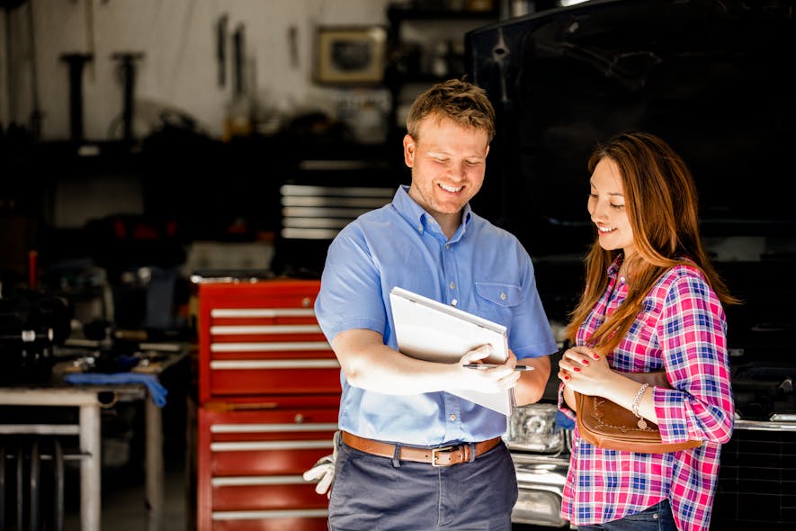 An auto technician reviews a warranty with a customer.