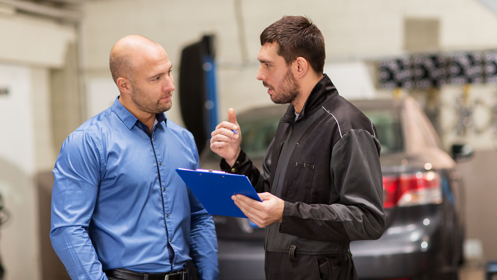 A shop manager talks to an auto technician.