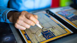 A basketball coach draws up a play on his board.