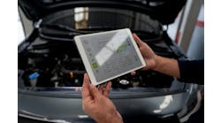 An automotive technician uses a tablet to get repair information to work on a car.