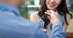 A service advisor hands a customer her keys. A service advisor hands a customer her keys.