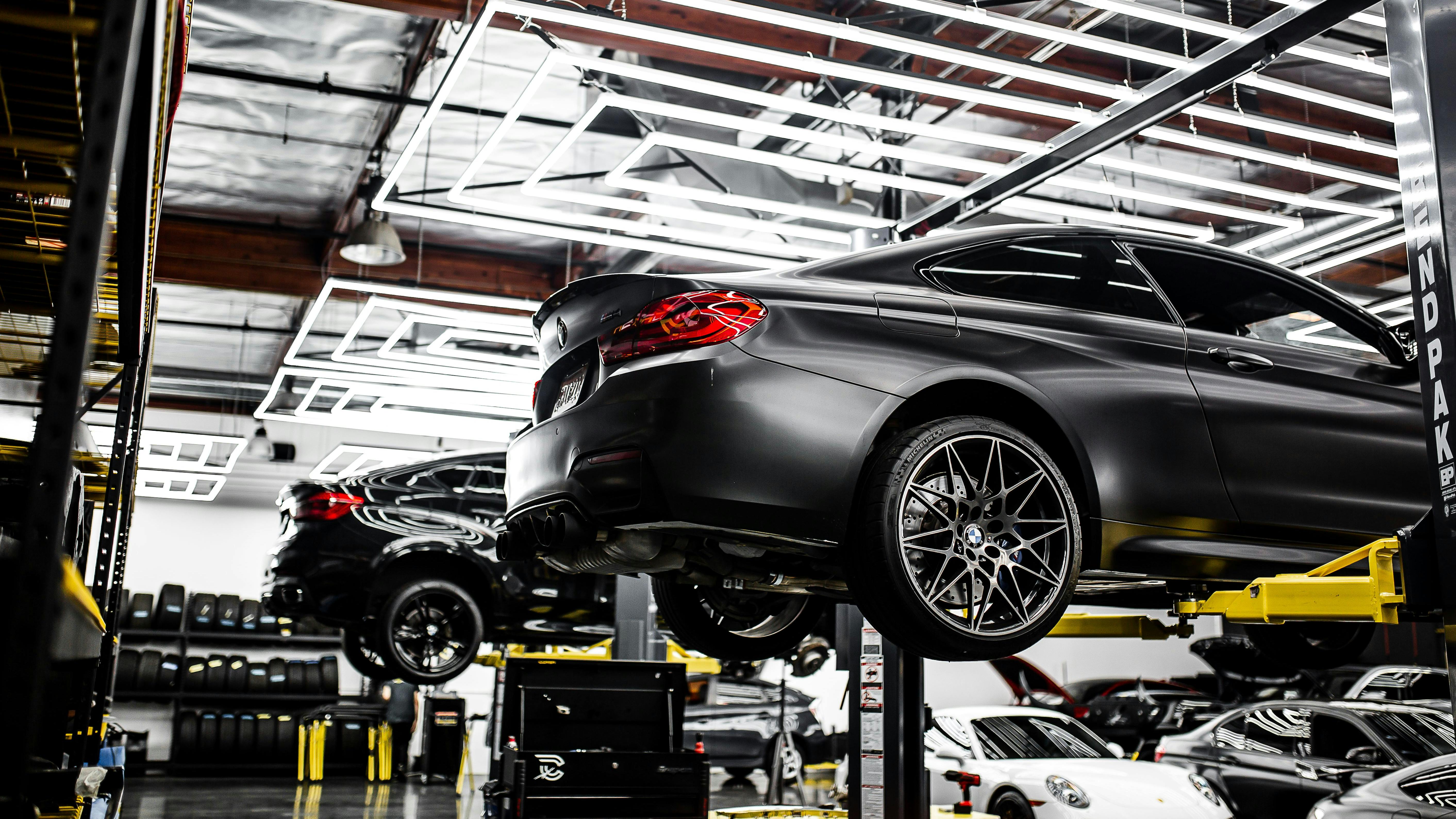 several vehicles on automotive lifts in a repair shop