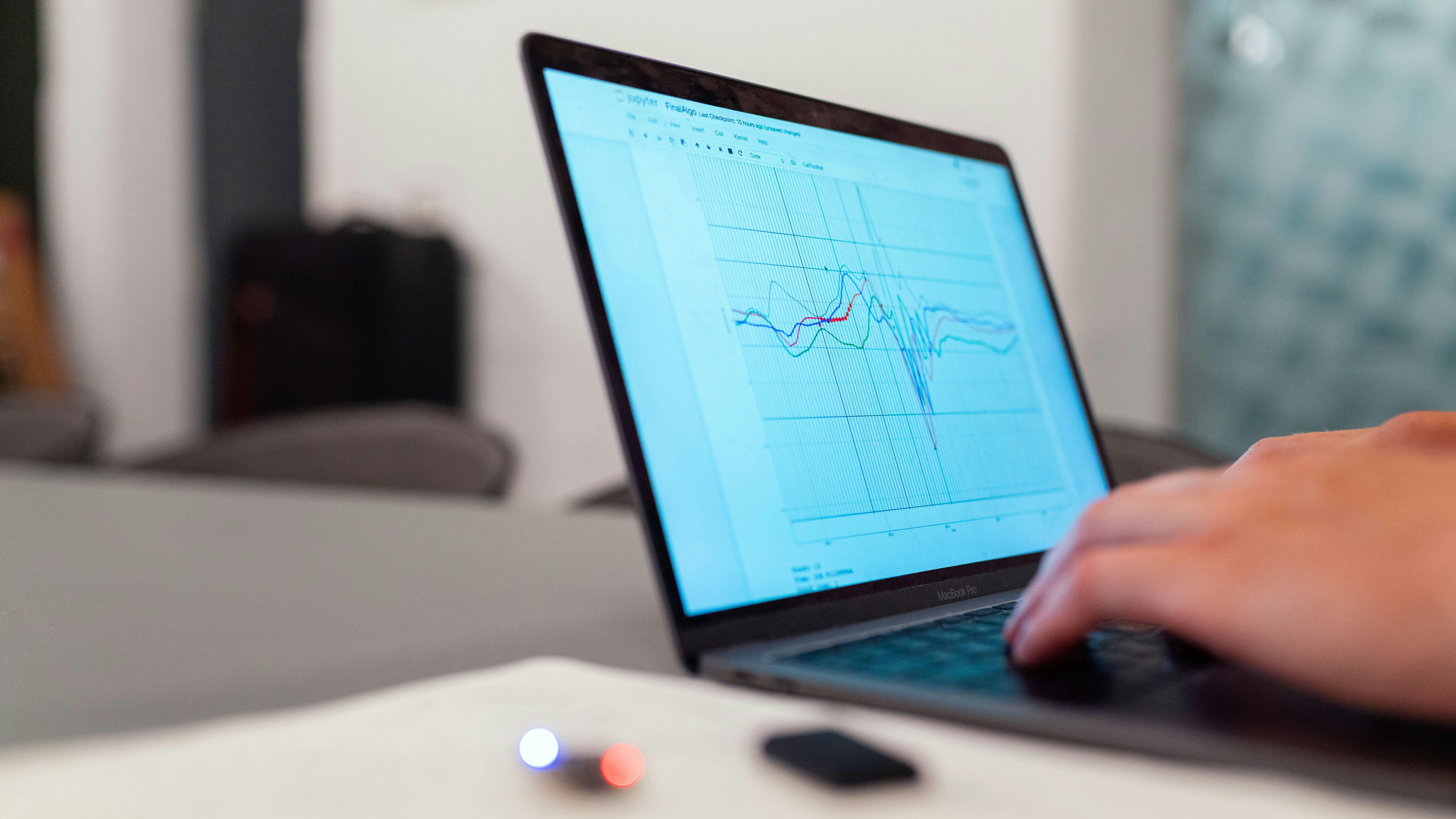 a man types on a laptop with data on the screen